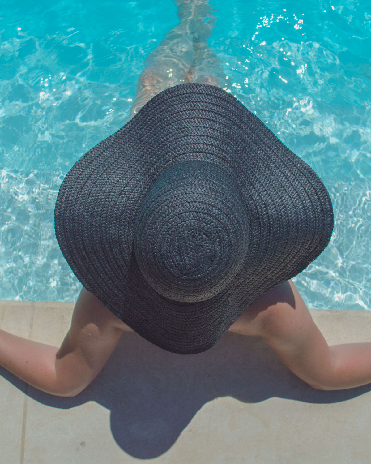 Woman in hat in pool in Cannes