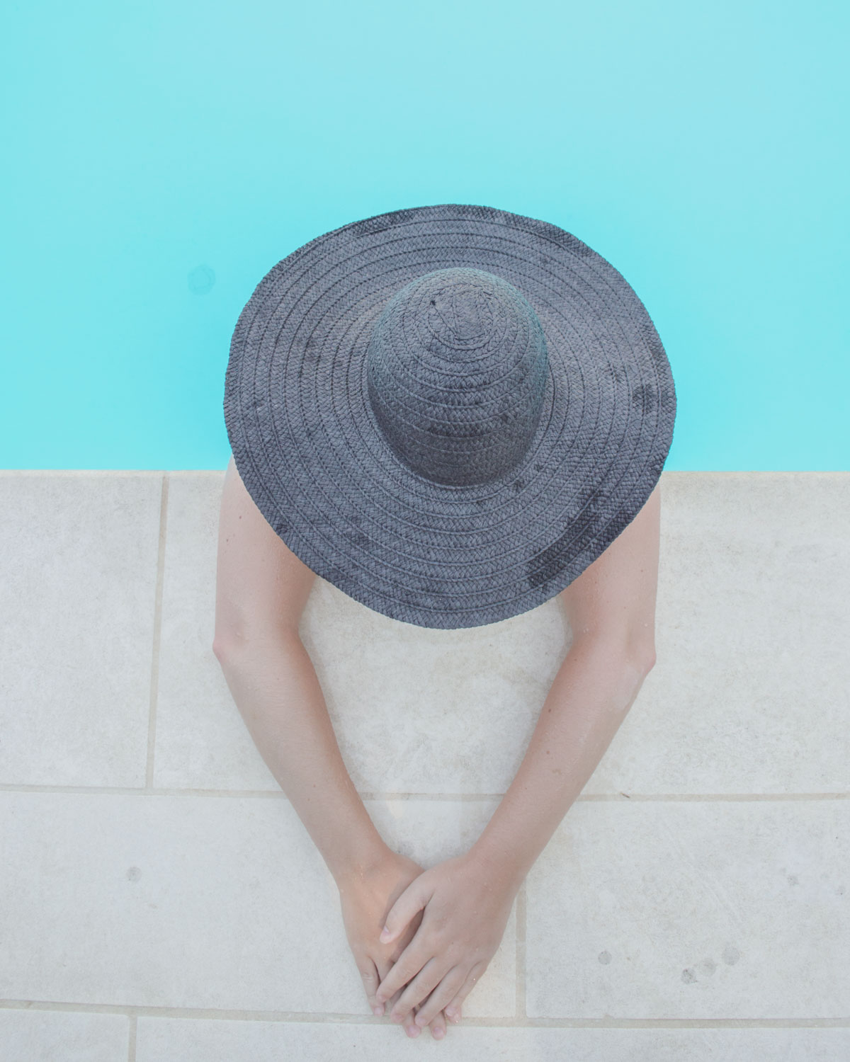 Woman with black hat in pool in Cannes, France